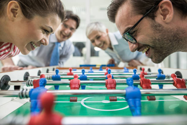 Close up of happy business colleagues having fun while playing table soccer on a break.