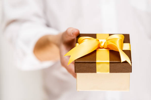 istock Male hand holding a gift box with ribbon. 667799596
