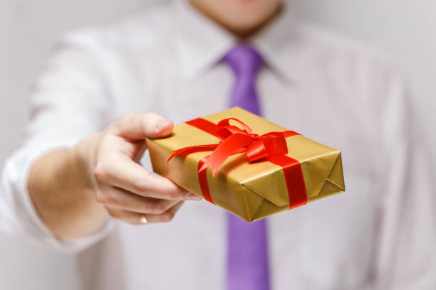 istock Male hand holding a gift box with ribbon. 667802026