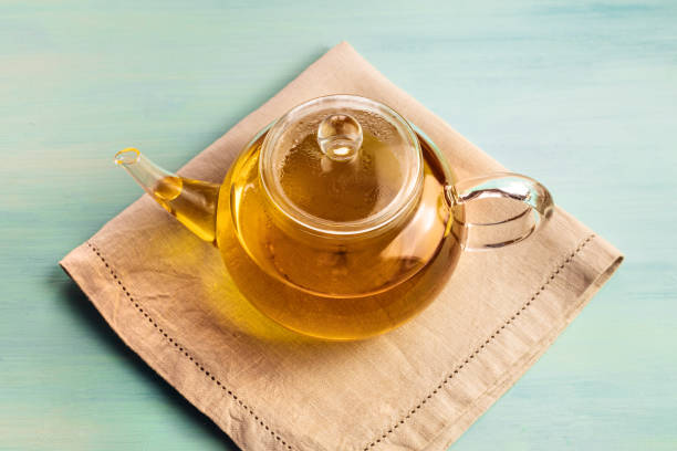 istock Teapot full of tea on teal texture with copyspace 667811218