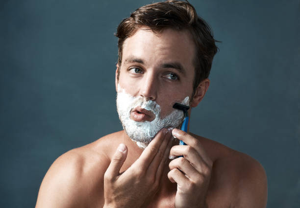 Keeping a clean shave Cropped shot of a handsome young man shaving against a grey background shaving stock pictures, royalty-free photos & images