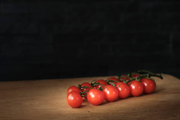 istock tomatoes branch on rustic table over dark background, healthy food 667817052