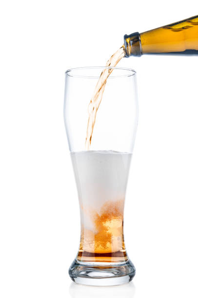 istock Beer pouring from bottle into glass isolated on white background 667819898