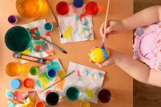 istock Little girl painting easter eggs with paintbrush 667822976