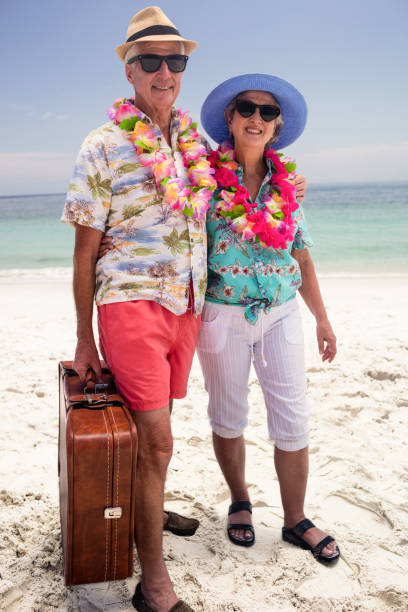 istock Happy senior couple holding suitcase on the beach 667823936