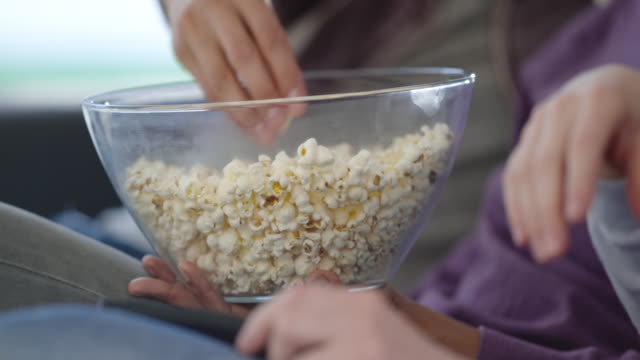 People taking popcorn from a bowl