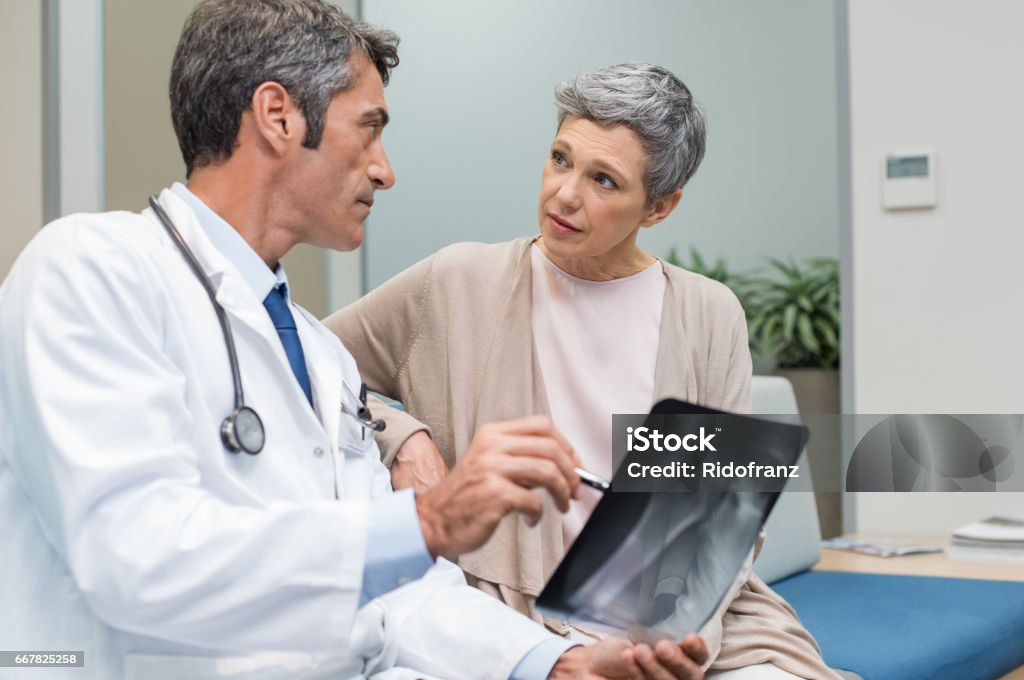 Doctor and senior patient Male doctor and senior patient discussing scan results at the office. Doctor showing to senior woman x-ray in a medical clinic. Mature doctor showing a radiography to his patient. Doctor Stock Photo