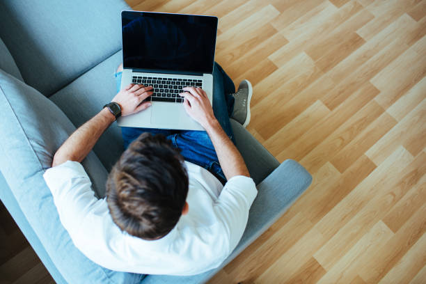 istock Overhead picture of  man using laptop sitting relaxed on sofa. 667825458