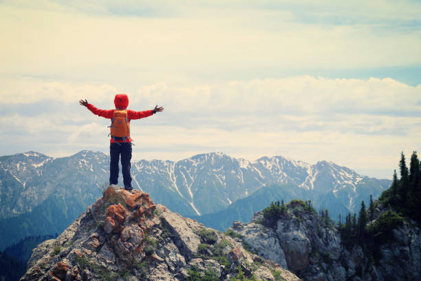 istock successful woman backpacker hiking on mountain peak cliff 667827804