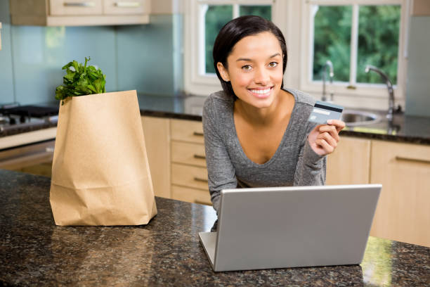 istock Smiling brunette using laptop and holding credit card 667828072