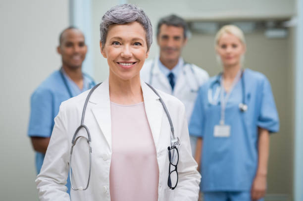 senior doctor with team - senior adult hospital uniform gray hair imagens e fotografias de stock