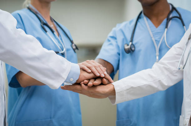 Teamwork at hospital Mature doctors and young nurses stacking hands together at hospital. Close up hands of medical team stacking hands. Group of successful medical doctors and nurses stack of hands. stacked hands photos stock pictures, royalty-free photos & images