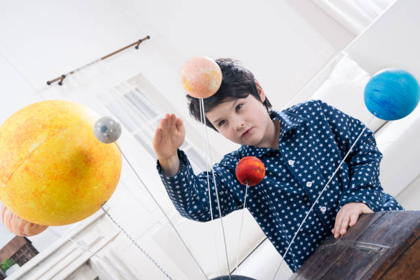 istock portrait of focused boy looking at planets models at home 667832310
