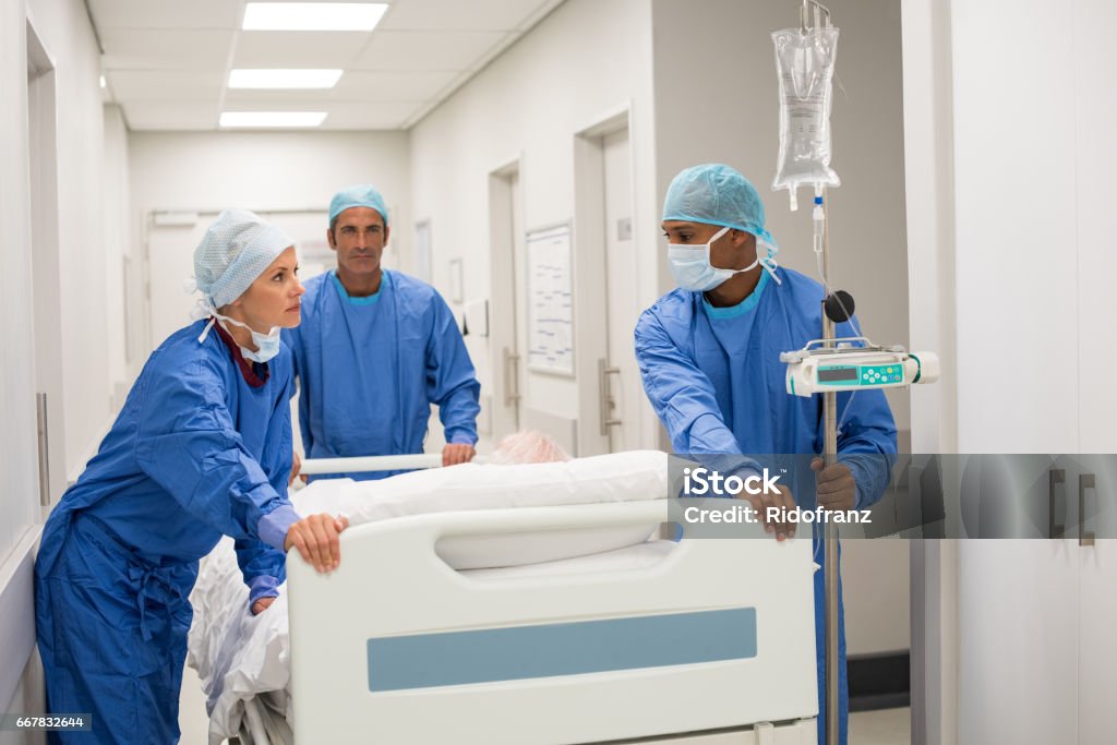 Urgent patient in hospital Patient hospital bed moved by medical staff to operating room. Surgeons pushing patient on bed into surgery. Medical team moving old patient on gurney through hospital corridor for an urgent operation. Emergency Medicine Stock Photo