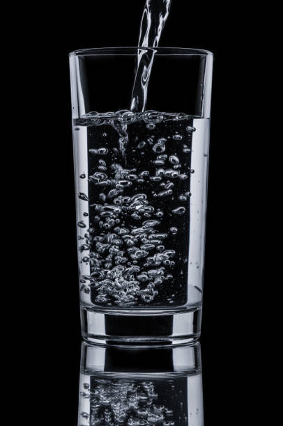 istock Pouring clear water in glass on black background 667832676