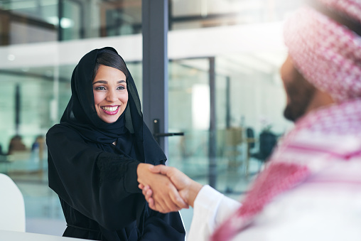 Shot of a young muslim businesswoman shaking hands with an associate in a modern office