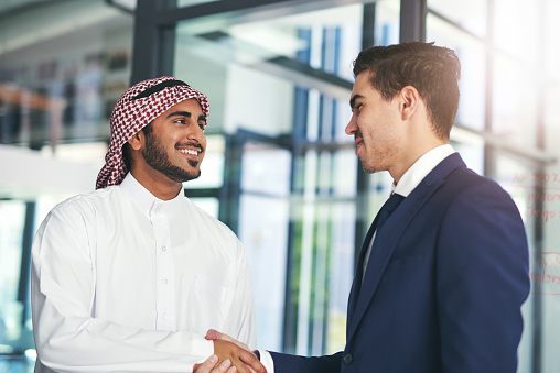 Shot of a young muslim businessman shaking hands with an associate in a modern office