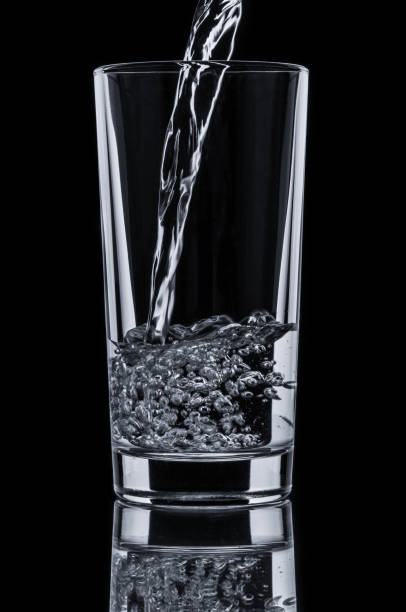 istock Pouring water into glass on black background 667835422