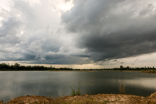 heavy storm clouds raining incoming over lake garden, dramatic