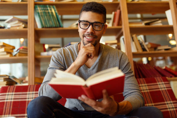 istock Smiling African American student enjoying book reading in library 667838334