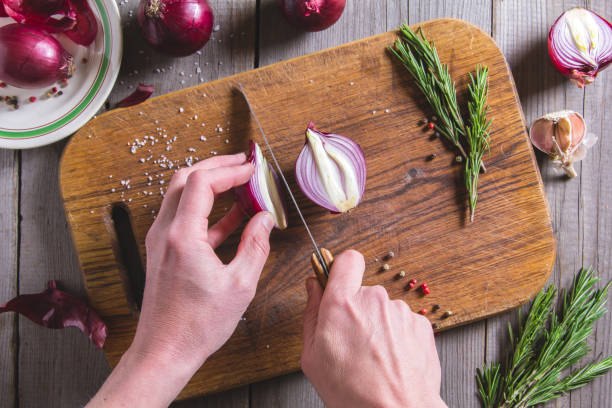 istock Chef cuts red onion on brown cutting board. 667838484