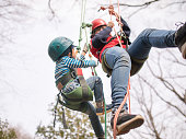 ロープを使って木に登る少年を助けるイベント スタッフ