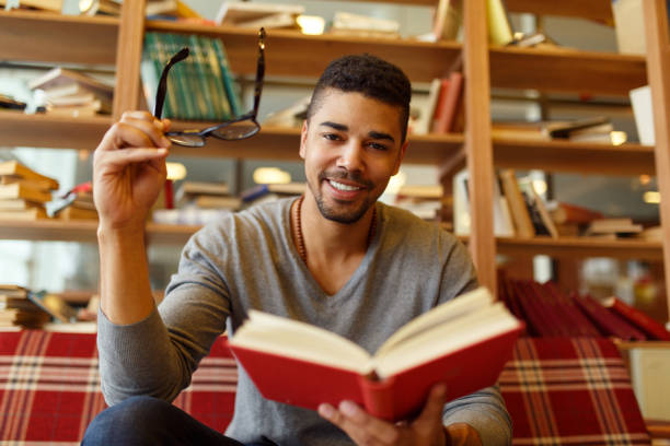 istock Smiling African American student enjoying book reading in library 667841502