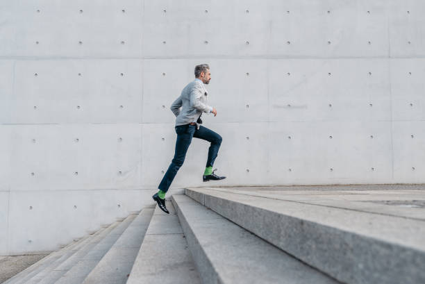 barbudo elegante empresario corriendo escaleras al aire libre - escalera fotografías e imágenes de stock