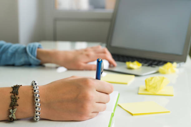 istock Female hands writing ideas on paper and working with laptop computer 667848962
