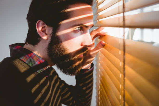 istock Hipster businessman peeking through blinds 667850760