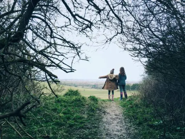 Photo of Two young friends on countryside walk pointing way forward