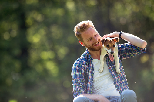 Shot of a handsome young man spending time with his dog in the park.
