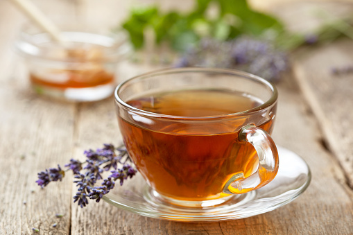 lavender tea in a glass cup, honey, lavender flowers on the old wooden background