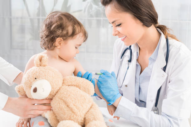 Vaccination little girl. Young woman pediatrician performs a vaccination of a little girl. The girl is holding a mascot. injecting flu virus vaccination child stock pictures, royalty-free photos & images