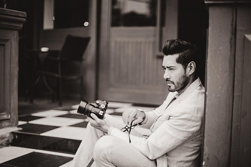 One man, modern and handsome holding a camera outdoors, black and white.