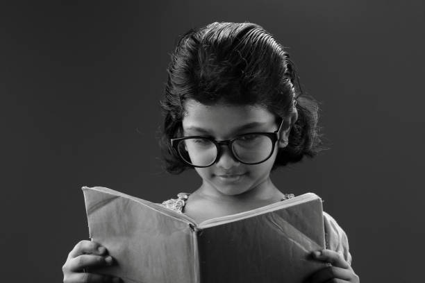 istock Girl wearing big spectacle reads a book 667903710