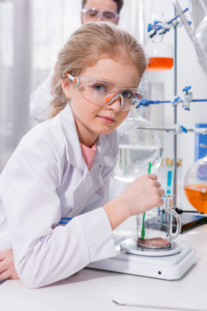 istock Cute little girl scientist in protective glasses making experiment in laboratory 667910846