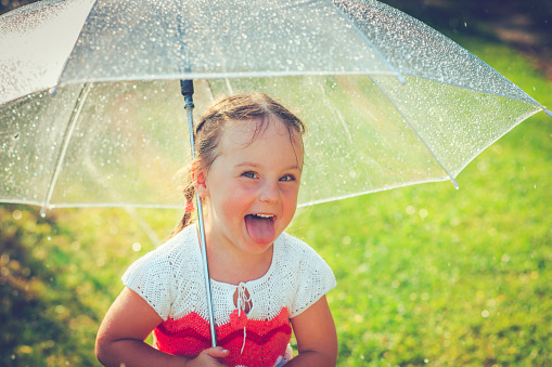 Little girl having fun in rain in summer