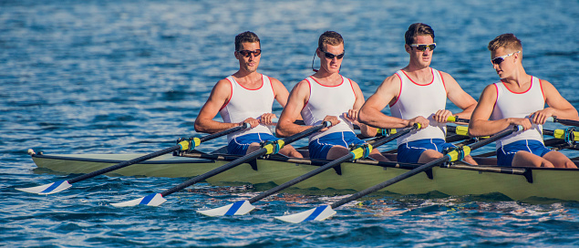 Side view of a coxless four training on a lake, panoramic.