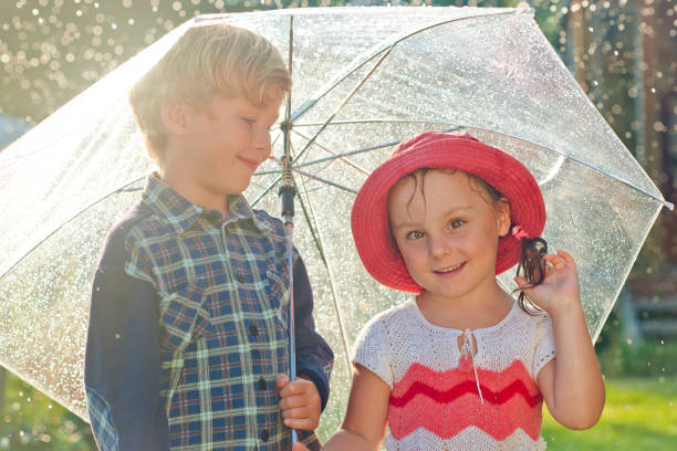 istock Happy girl and boy in rain 667924554