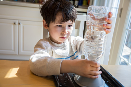 Little boy with a water bottle and motor making a water tornado