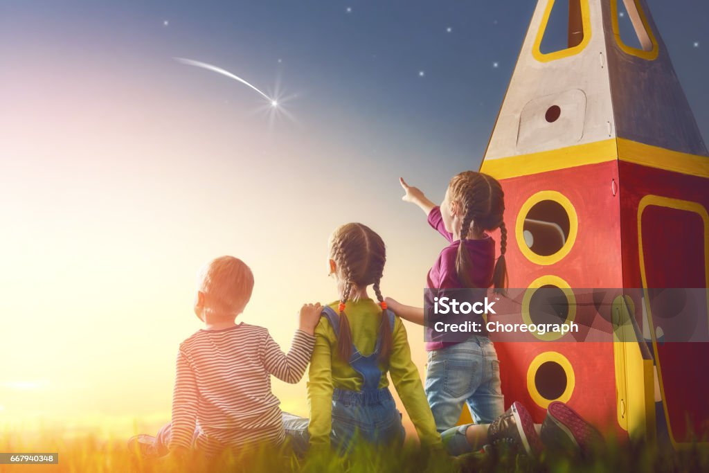 kids looking at the sky Children playing with toy rocket and dreaming of becoming a spacemen. Portrait of funny kids looking at the sky. Family friends games outdoors. Boy and girls make a wish by seeing a shooting star. Child Stock Photo