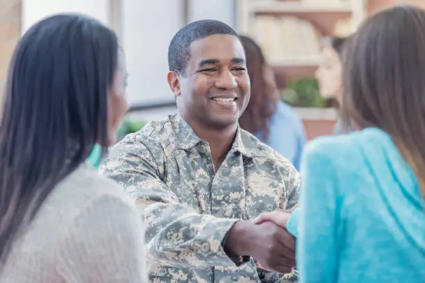 Photo of Smiling military recruiter greets students at recruitment event