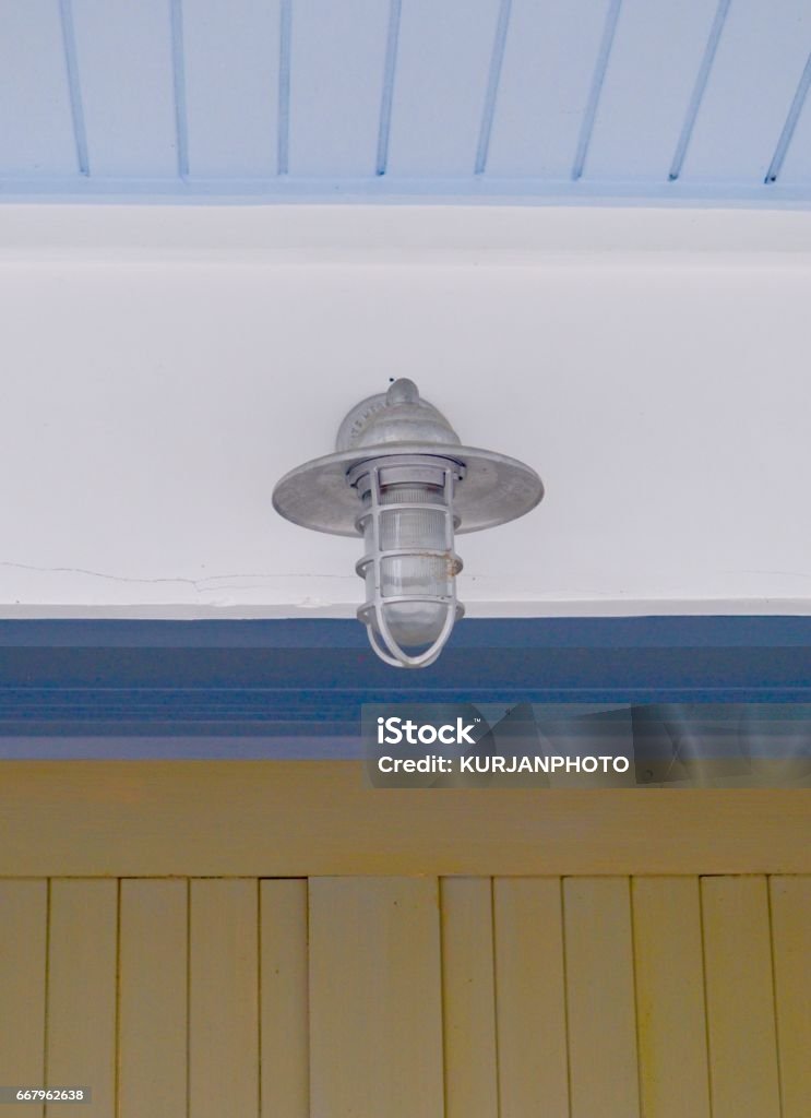 Outdoor Ceiling Light Fixture with Blue Ceiling Outdoor light fixture with blue ceiling and brown wall. Beadboard Stock Photo