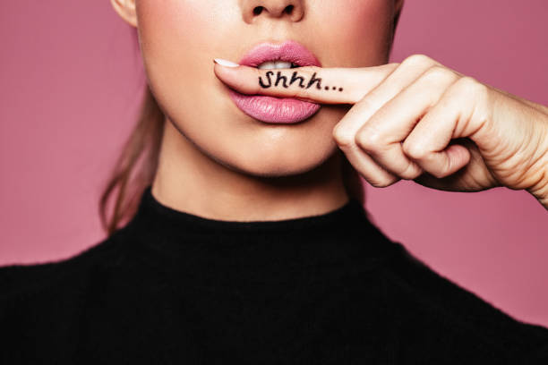 Shh! Women's secrets Shh! Women's secrets. Cropped shot of female with finger in mouth. Closeup portrait of young woman is showing a sign of silence with shhh written on the finger. Sensuality stock pictures, royalty-free photos & images