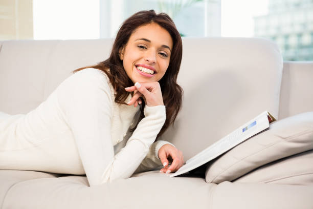 istock Pretty brunette reading magazine on the couch 667984086