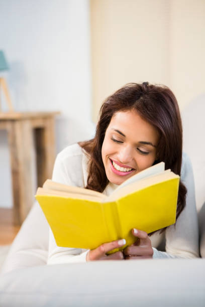 istock Peaceful woman lying on couch reading a book 667984244