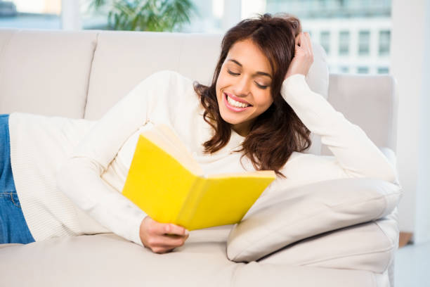 istock Peaceful woman lying on couch reading a book 667985354