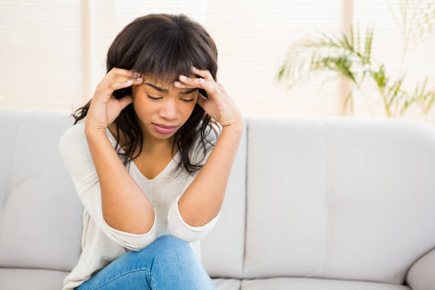 istock Stressed woman holding her head on couch 667990044