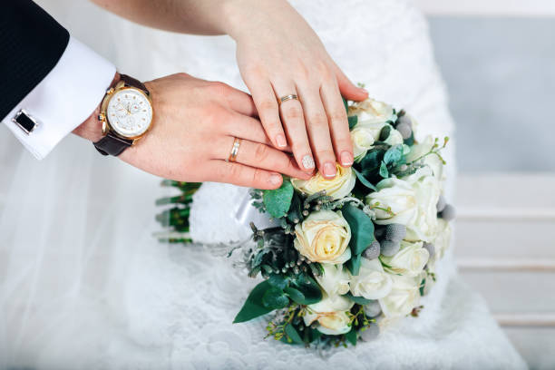 istock Bride hands with ring and wedding bouquet of flowers 668001632